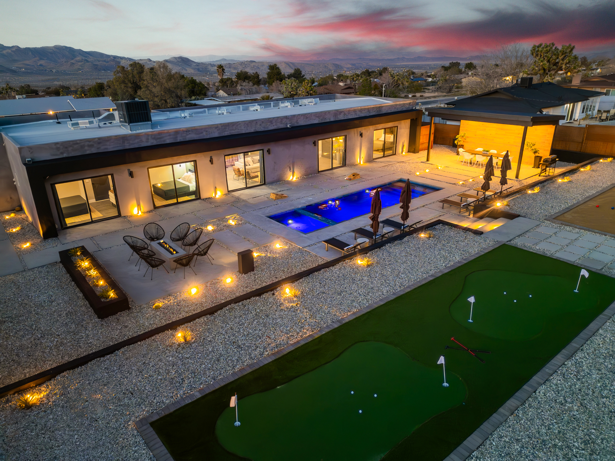 Aerial twilight view of Desert Ace's pool, putting green, and desert mountains